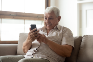Older man sitting on sofa with mobile phone