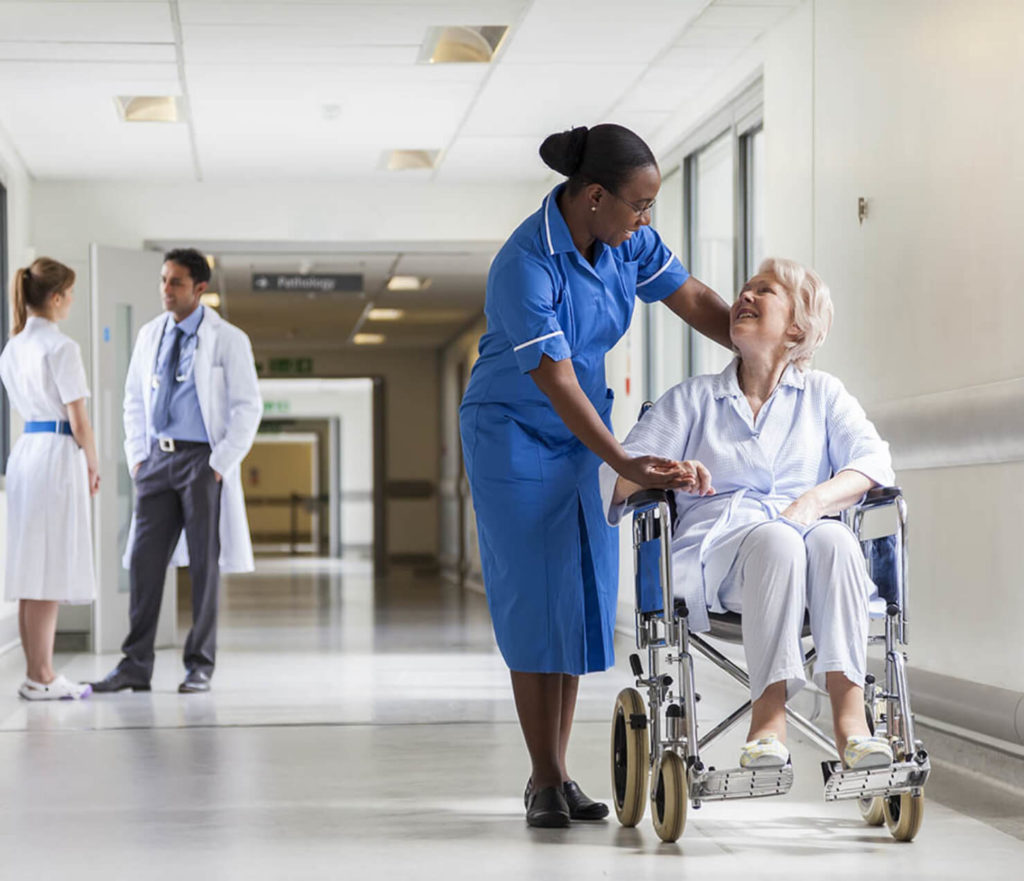 A nurse talks to a woman in a wheelchair in an hospital corridor