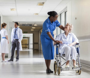 A nurse talks to a woman in a wheelchair in an hospital corridor