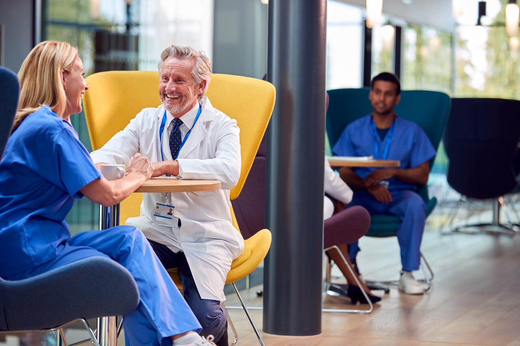 Two clinicians sitting down on chairs facing each other and smiling