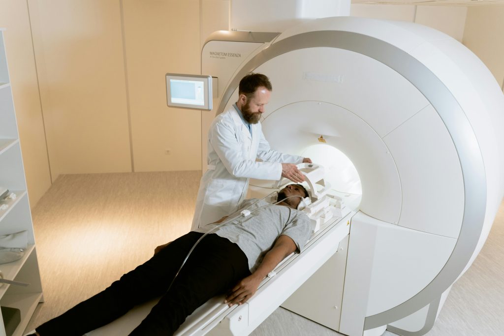 A doctor standing over a man about to go into an MRI machine