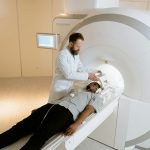 A doctor standing over a man about to go into an MRI machine