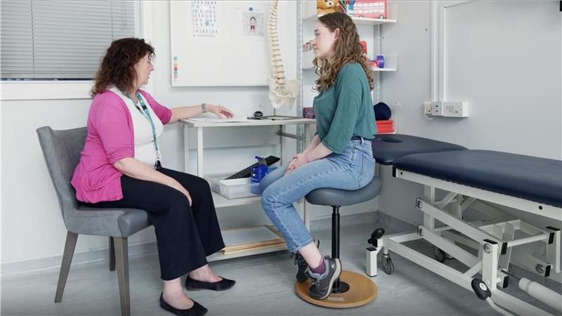 A young woman in a surgery talking to a female practitioner.