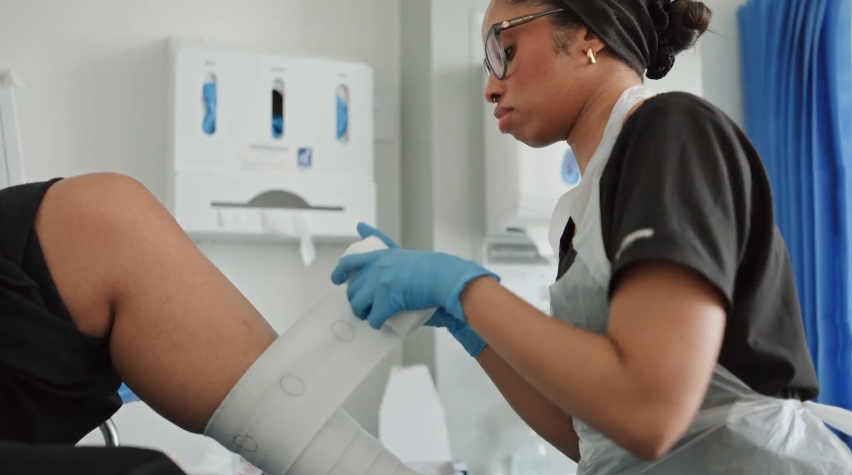 Nurse wrapping a patient's leg in compression bandages.